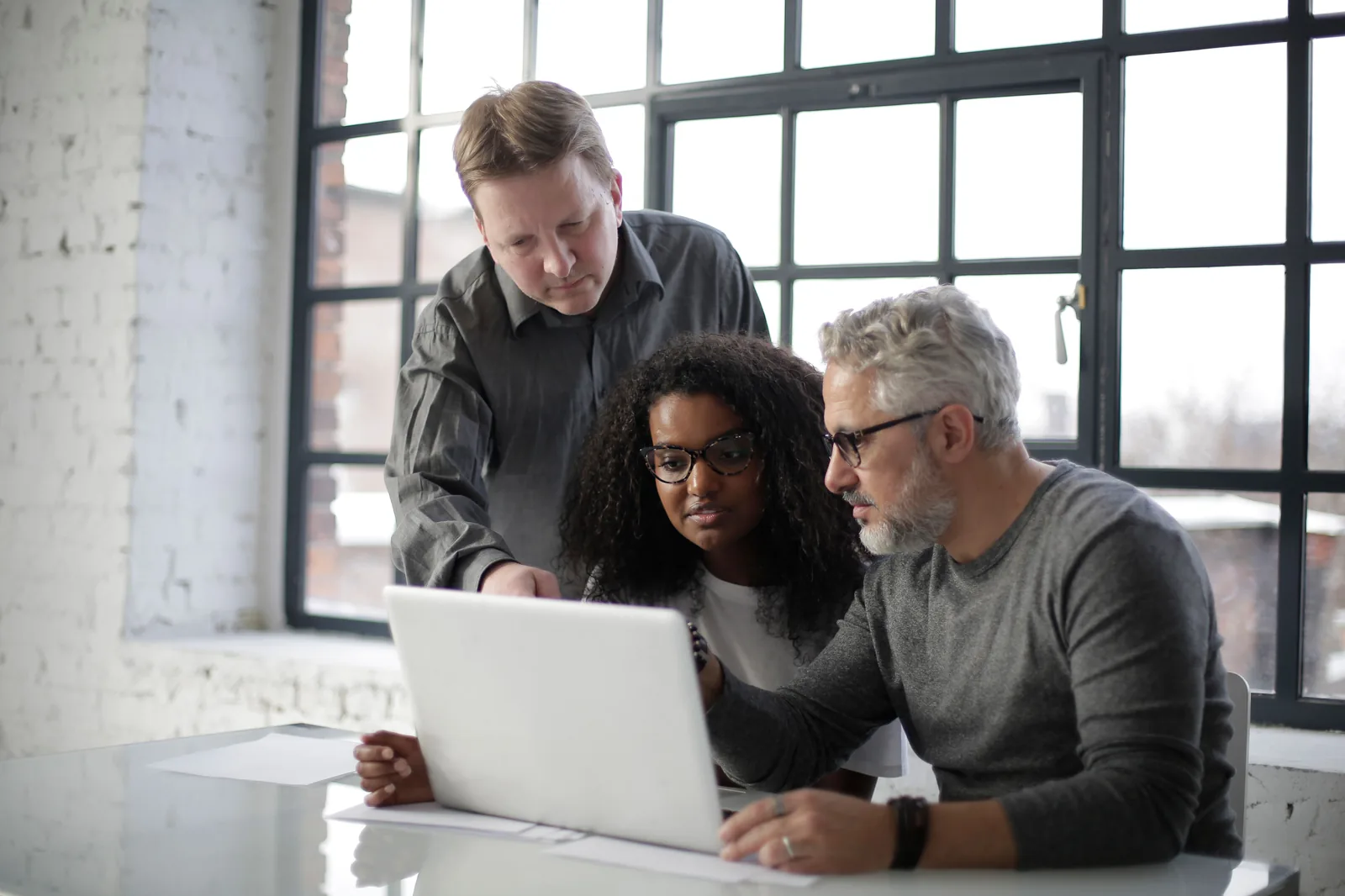 Professionals collaborating around a laptop in a bright modern office